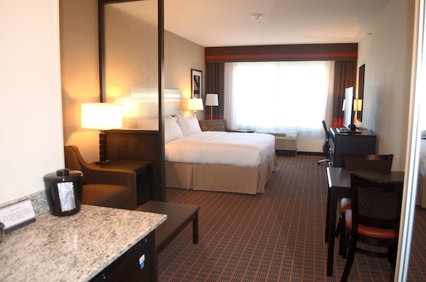 A hotel room with a bed, a desk, a chair, a coffee maker, and a television. - Holiday Inn Express & Suites Golden - Denver Area by IHG (Golden)