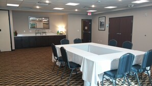 A conference room with a long table, chairs, a carpeted floor, a kitchenette, and a door marked "EXIT". - Holiday Inn Express & Suites Golden - Denver Area by IHG (Golden)