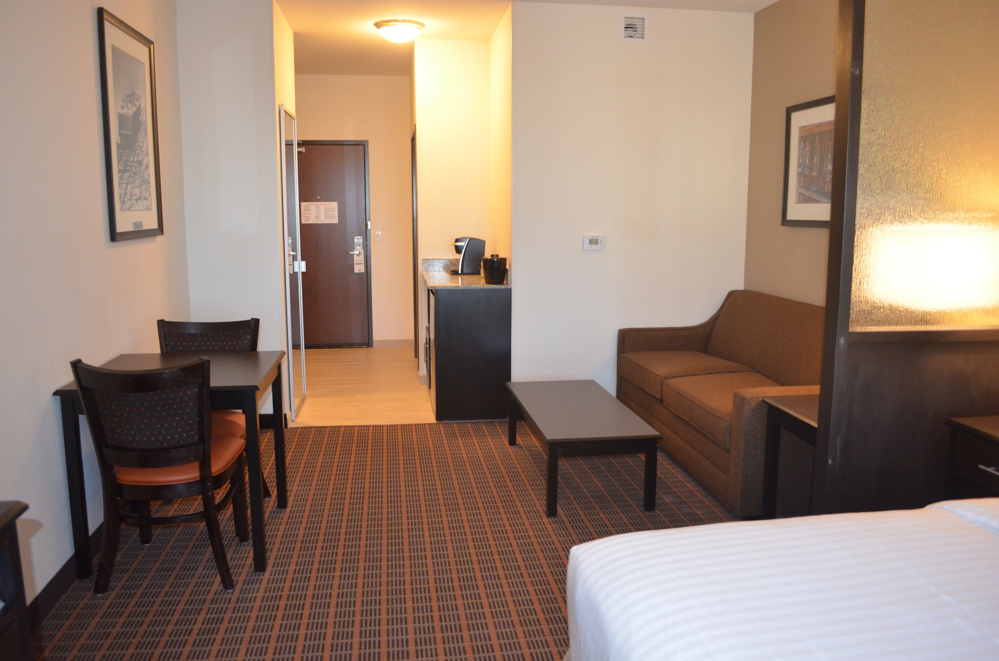 A hotel room with a bed, a desk with a chair, a sofa, and a small table.