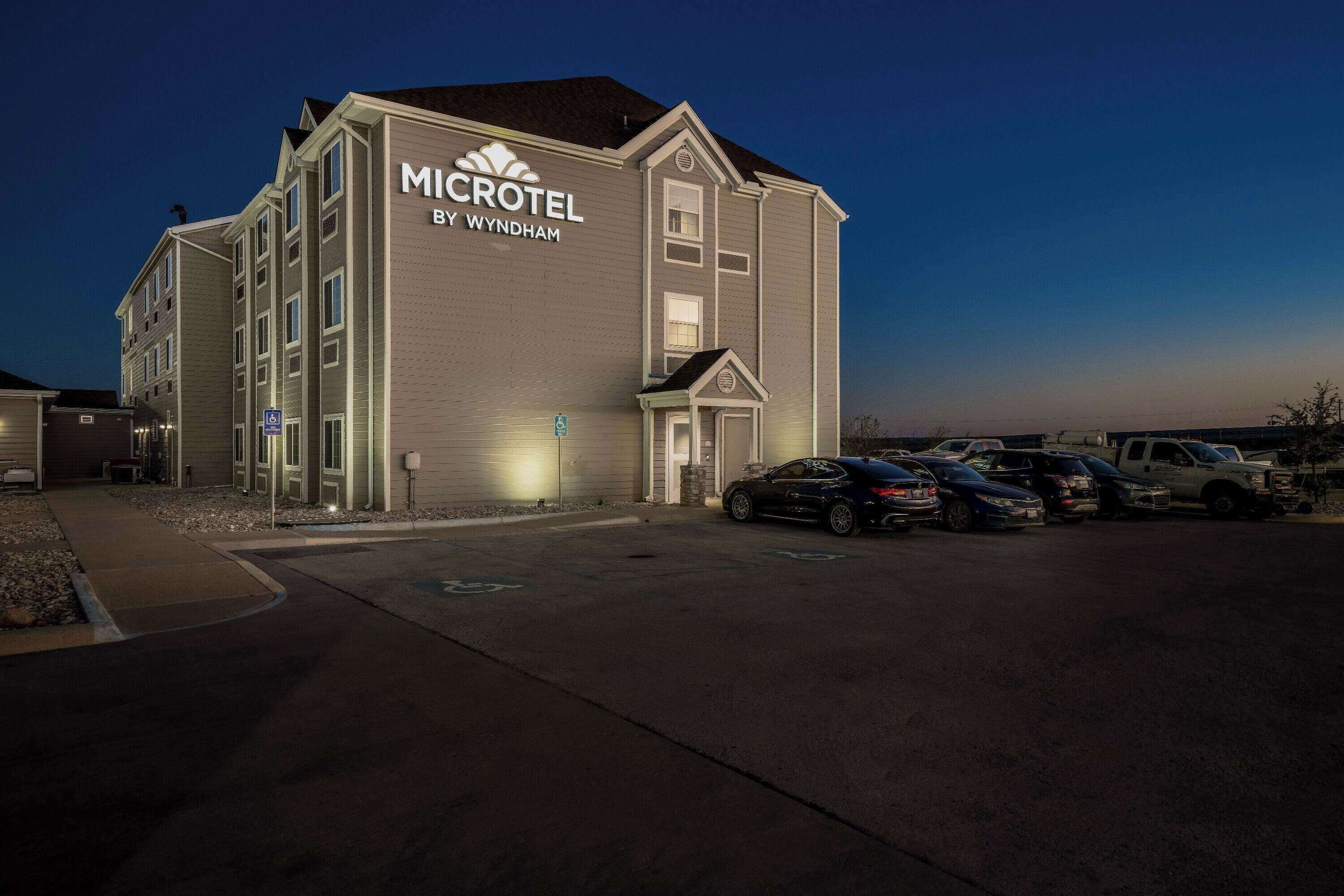 Ett Microtel by Wyndham-hotell med en parkeringsplats och flera bilar parkerade framför.