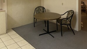 Une pièce avec une table ronde, deux chaises, un luminaire au plafond et une porte.