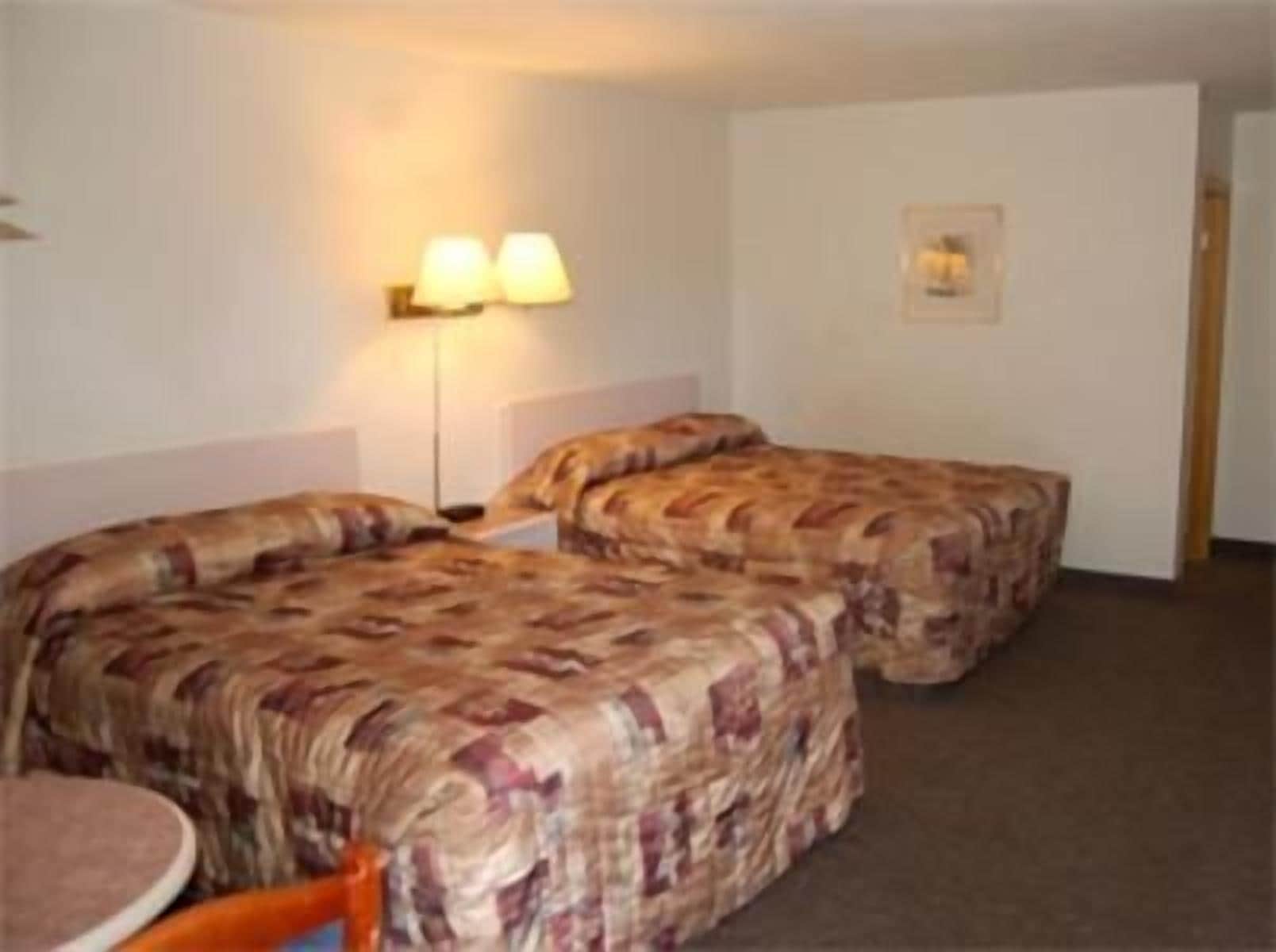Een hotelkamer met twee bedden, een kleine tafel en een lamp.