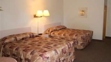 Een hotelkamer met twee bedden, een kleine tafel en een lamp.