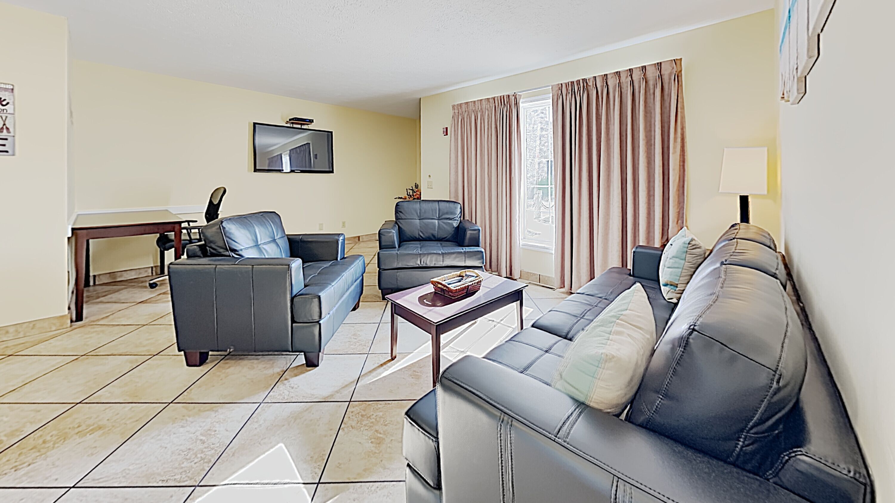 A living room with two sofas, a coffee table, and a flat-screen TV mounted on the wall.