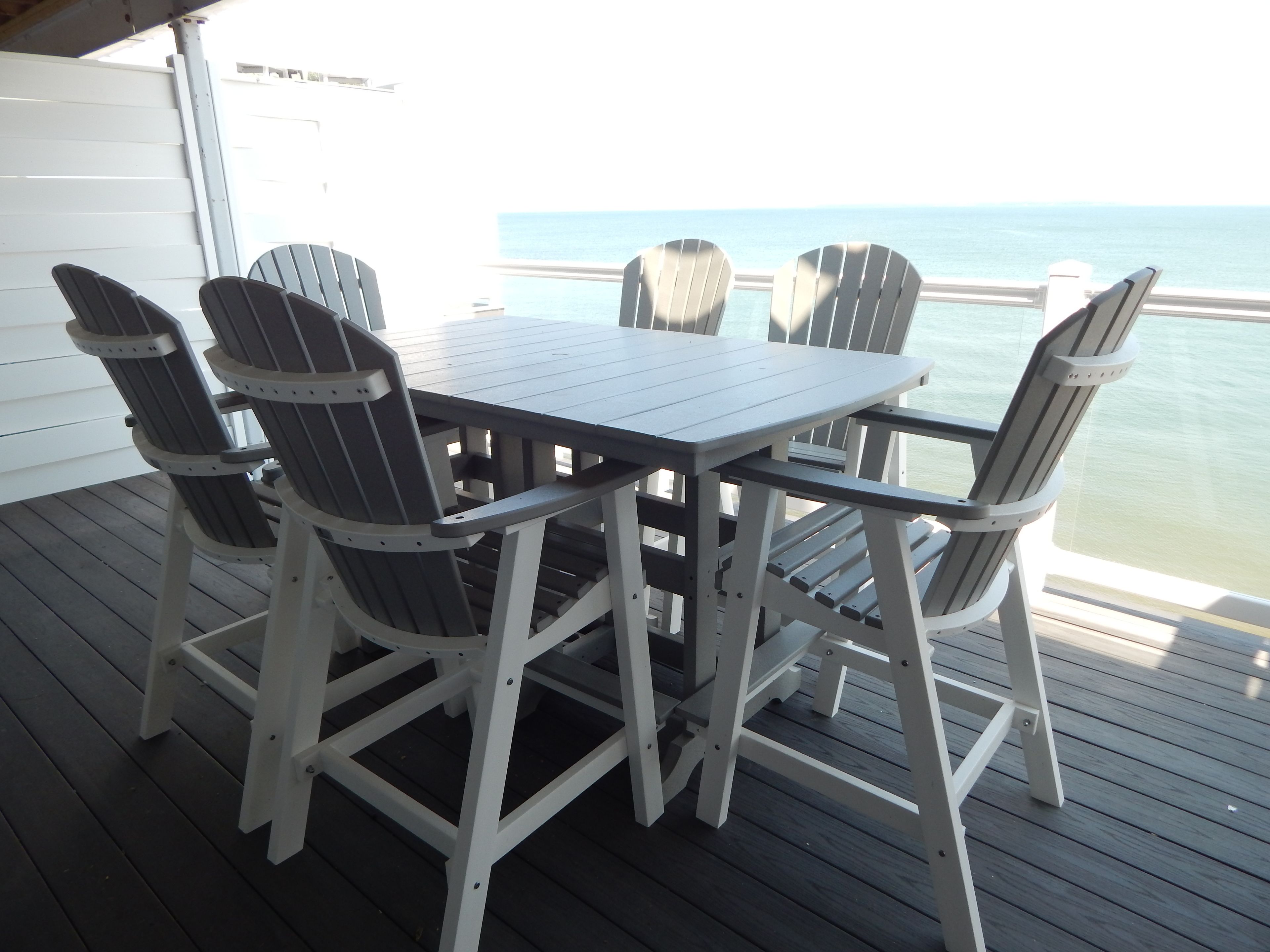 Une terrasse avec une table et quatre chaises, donnant sur une étendue d’eau.