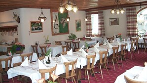 Comedor con mesas y sillas de madera, lámparas colgantes y adornos en las paredes.