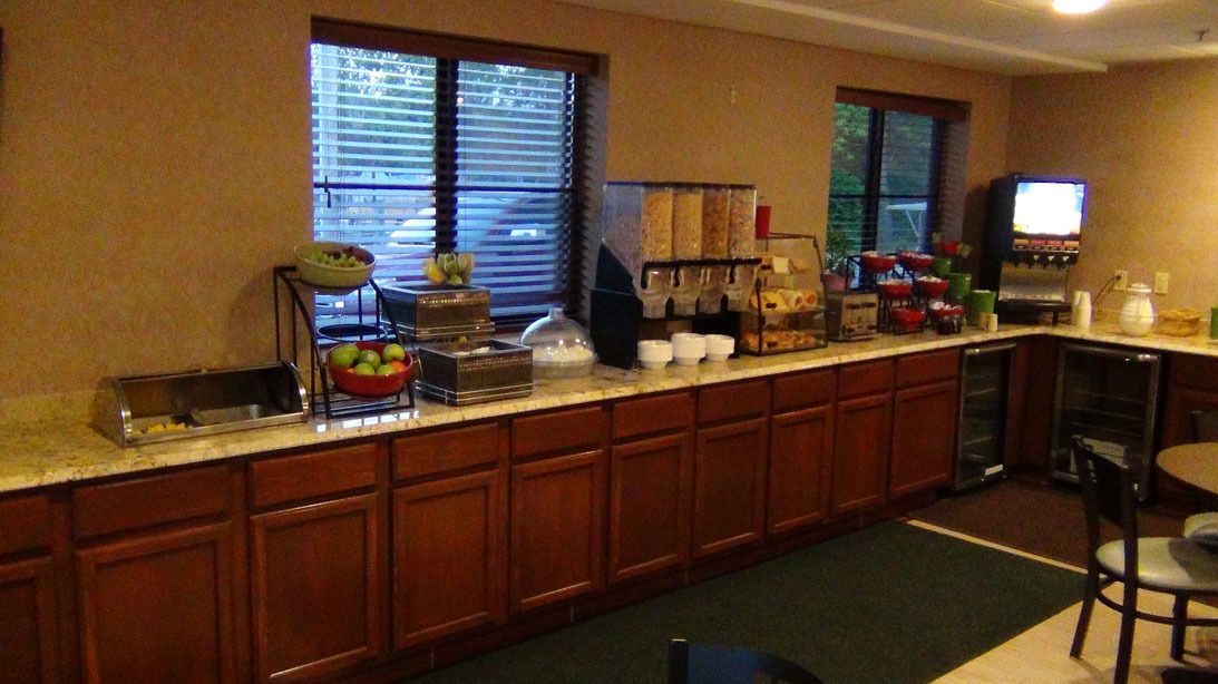 A hotel kitchen with a long counter, a coffee station, and a television.