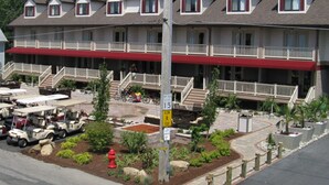 A multi-story hotel with a red awning, outdoor seating, and a landscaped front yard. - Put-In-Bay Resort and Conference Center (Put-in-Bay)