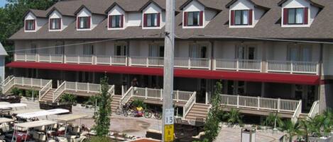 A multi-story hotel with a red awning, outdoor seating, and a landscaped front yard.