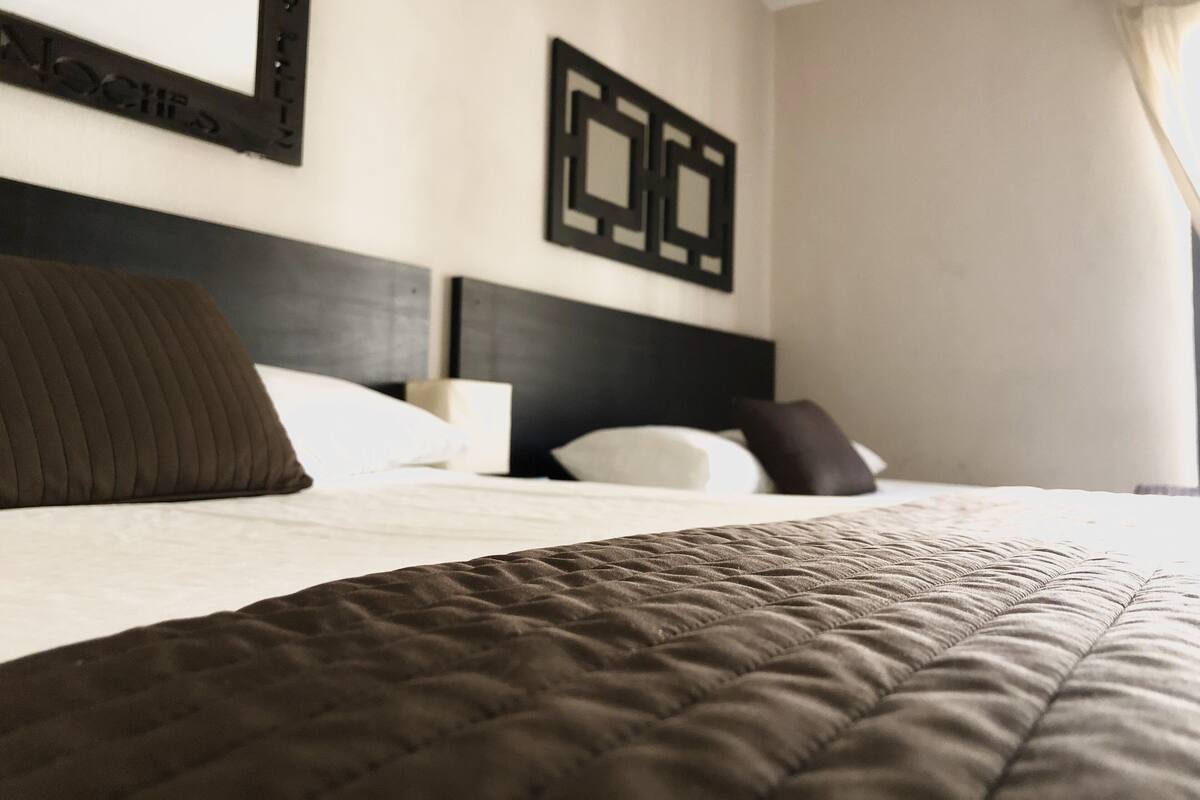 A neatly made bed with a dark brown quilt, white pillows, and a black headboard.