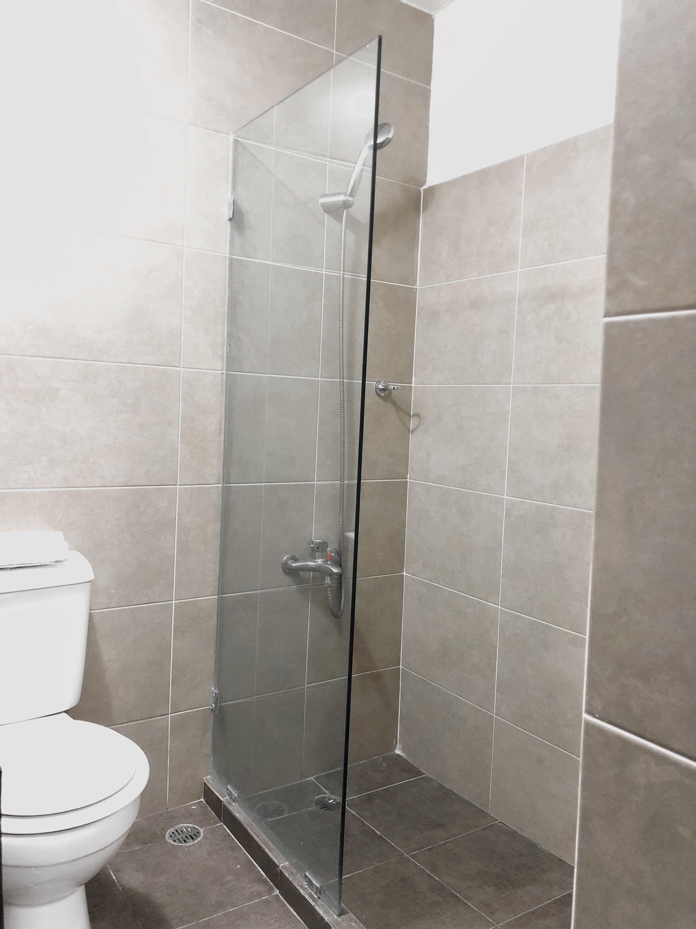 Ein Badezimmer mit Duschkabine, Toilette und Fliesenwänden.