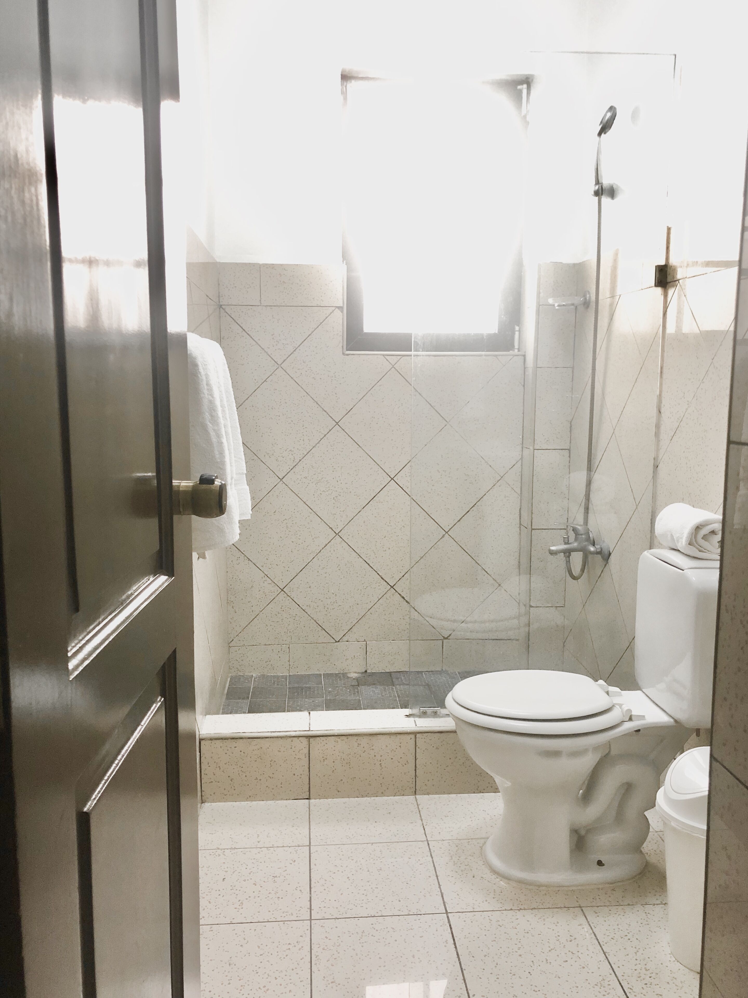 Een badkamer met toilet, douche en betegelde vloer.