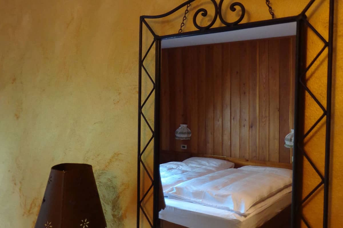 A bed with a headboard, a lamp, and a wall-mounted mirror.