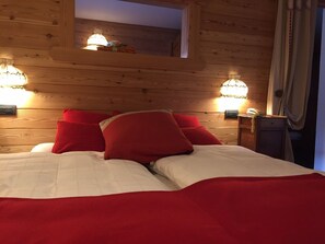 A wooden cabin room with a bed, red pillows, and two wall-mounted lamps. - ALBERGO ALPENROSE Ski&Bike Mountain Hotel (Gressoney-Saint-Jean)
