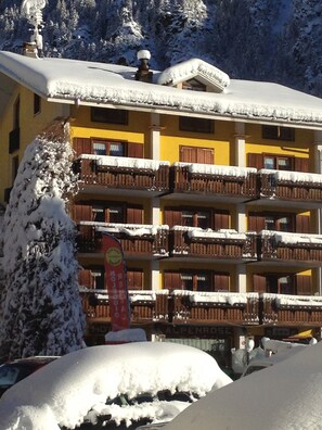 A multi-story building with balconies covered in snow, surrounded by snow-covered trees. - ALBERGO ALPENROSE Ski&Bike Mountain Hotel (Gressoney-Saint-Jean)