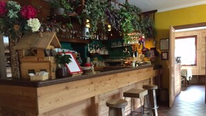 A rustic bar area with wooden bar counter, stools, and hanging plants. - ALBERGO ALPENROSE Ski&Bike Mountain Hotel (Gressoney-Saint-Jean)