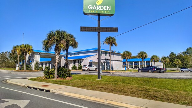 Un hôtel Garden Inn & Suites avec un toit bleu et des palmiers à l’avant.