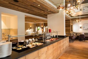 Een buffetgedeelte met een houten plafond, glazen scheidingswanden en diverse soorten eten.