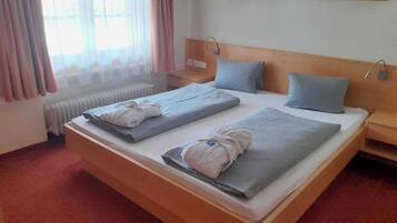 Une chambre d’hôtel avec un grand lit, deux oreillers, une table de chevet et une fenêtre avec des rideaux.