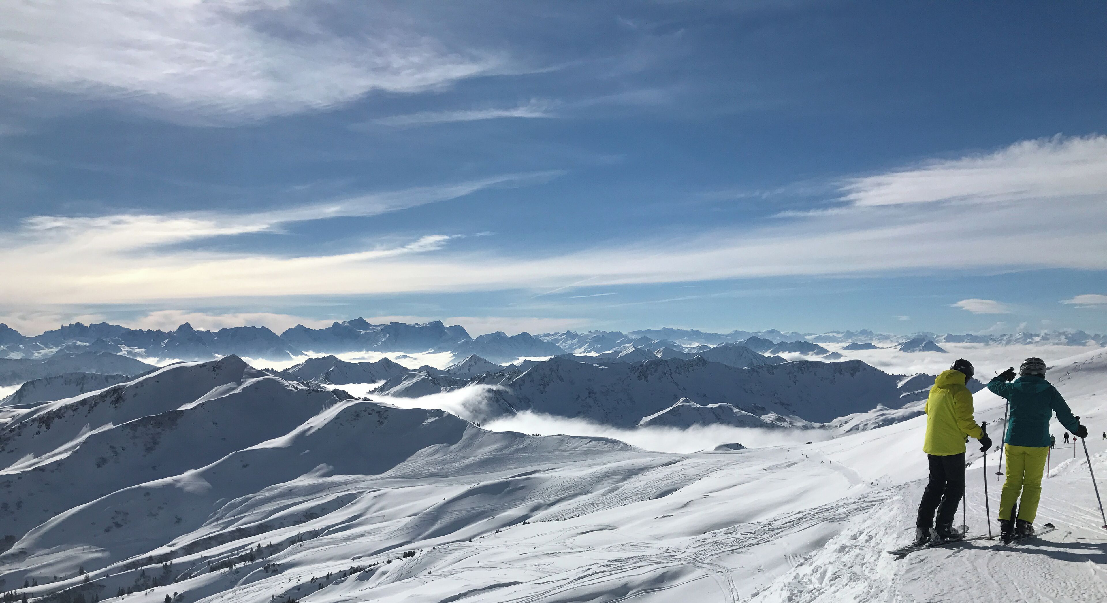 Paisaje nevado de montaña con dos esquiadores.