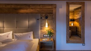 A bedroom with a wooden headboard, a bedside table with a lamp, and a mirror on the wall.