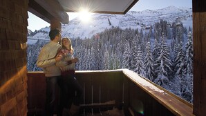 A couple on a balcony with a view of snow-covered trees and mountains. - Alpine Lifestyle Berghotel Madlener (Damüls)