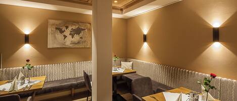 A restaurant with wooden tables and benches, a world map on the wall, and wall-mounted lighting.