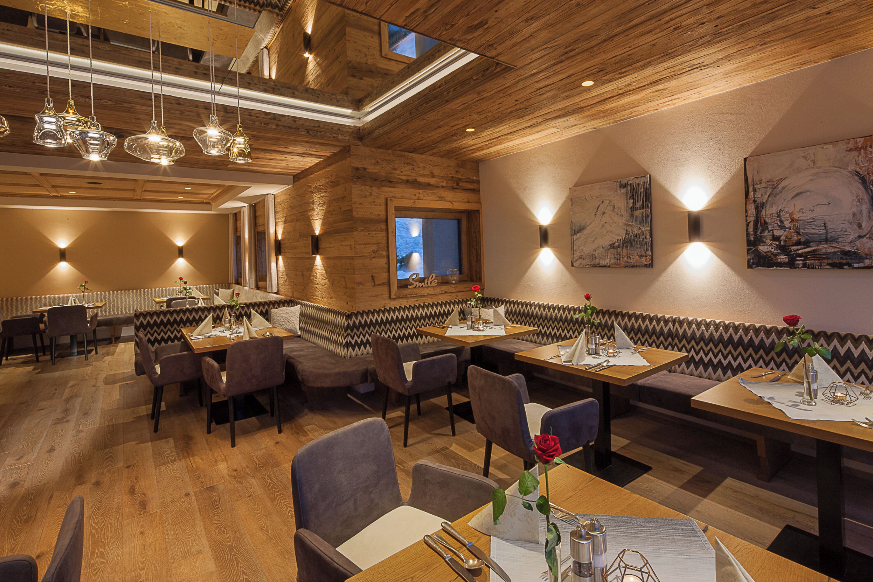 A restaurant with wooden ceiling and walls, multiple dining tables, and booths.