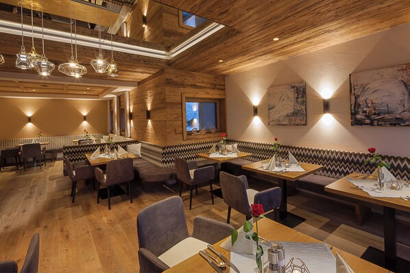 Un restaurante con techo y paredes de madera, varias mesas para comer y cabinas.