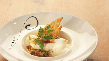 A white plate with a fish dish, garnished with parsley, and a piece of bread.