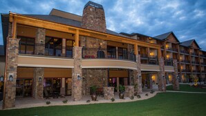 A multi-story hotel with a stone facade, outdoor seating area, and a well-maintained lawn. - The Lodge at Old Kinderhook Golf Resort (Camdenton)