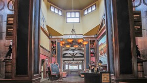 A lobby with a chandelier, wooden columns, a reception desk, and a mural on the wall. - The Lodge at Old Kinderhook Golf Resort (Camdenton)