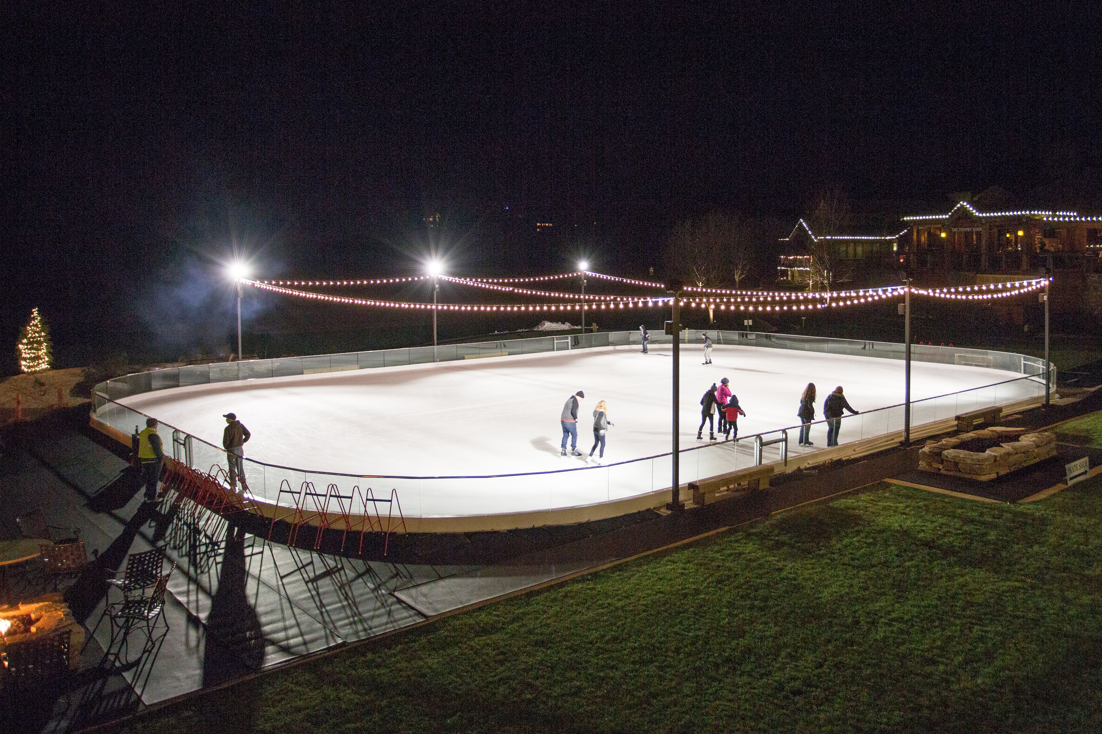 Una pista de hielo al aire libre de noche con gente patinando y conversando.