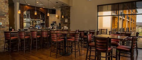 A restaurant with wooden flooring, red upholstered chairs, and hanging pendant lights.