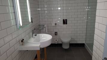 A modern bathroom with white subway tiles, a white sink with a mirror, and a toilet.