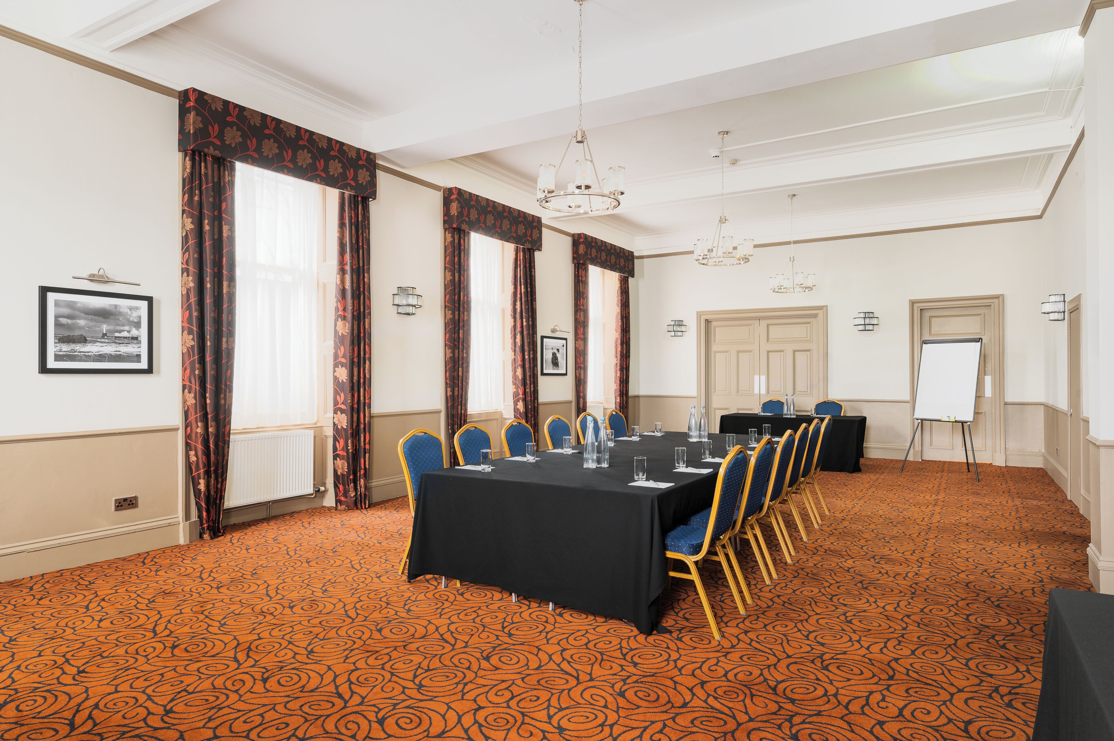 A conference room with a long table, blue chairs, and a whiteboard.