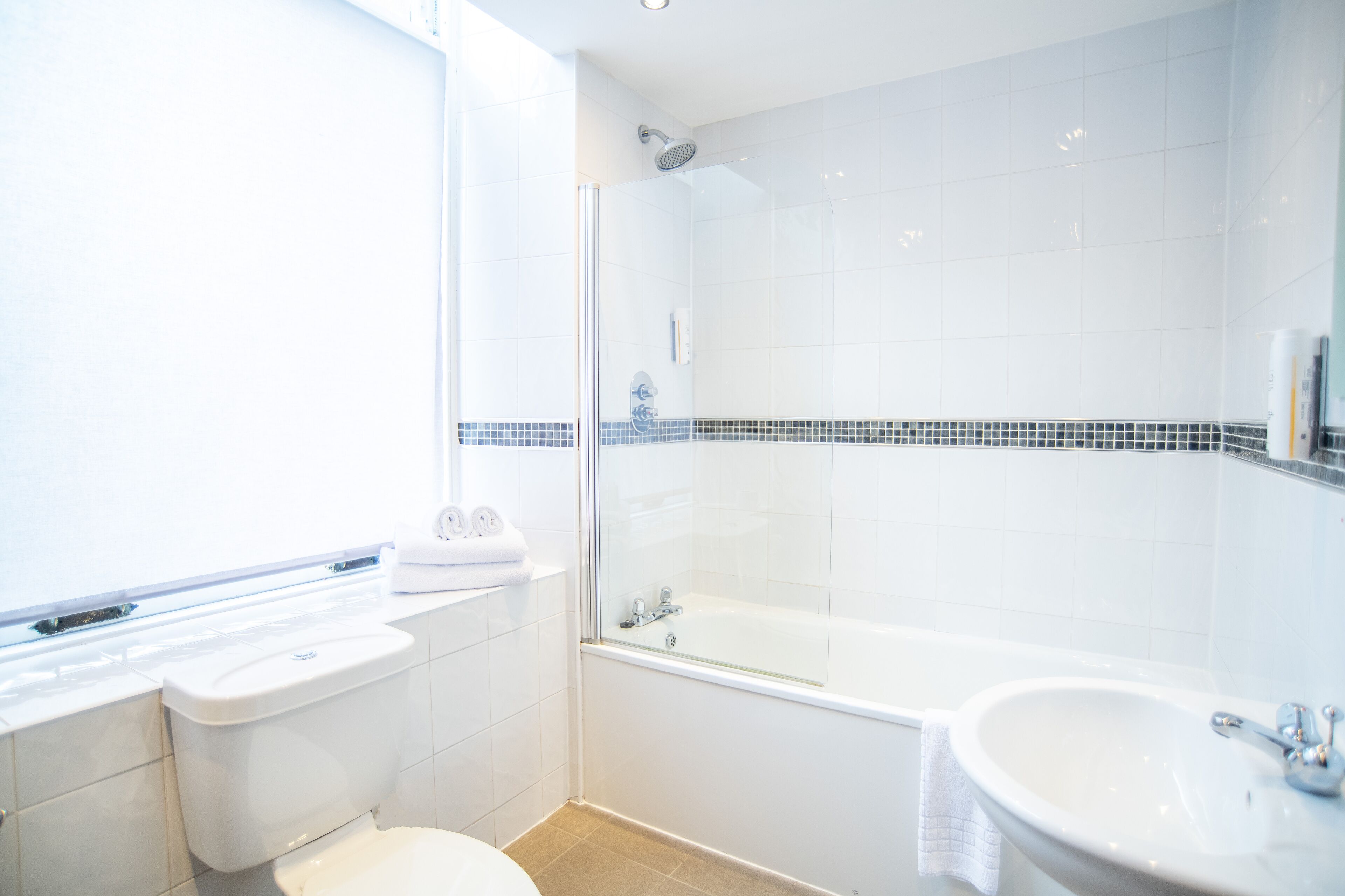 A modern bathroom with a glass-enclosed shower, a white sink, and a toilet.