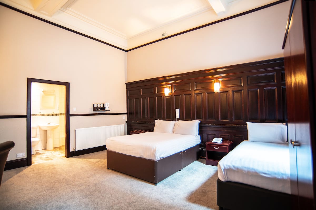 A bedroom with a large bed, a bedside table, a nightstand, and a wardrobe.