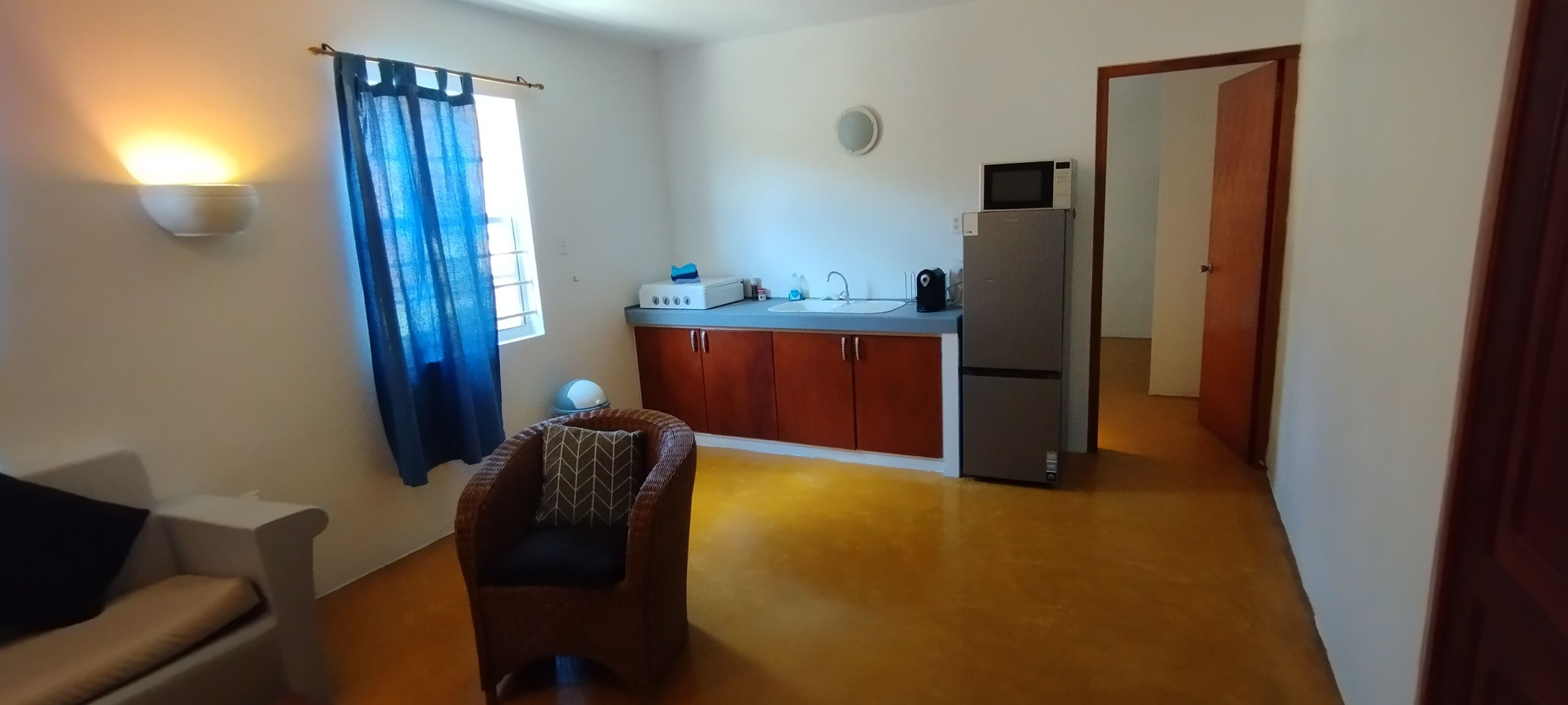 A compact living space with a kitchenette, a dining area, and a seating area with a chair.