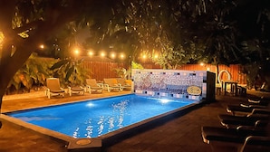 A swimming pool with lounge chairs and a mosaic wall. - Dive Hut - Boutique Apartments (Kralendijk)