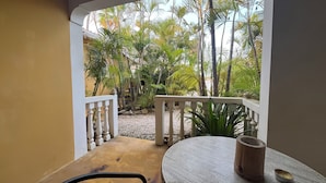 A balcony with a view of tropical plants and a round table with a candle. - Dive Hut - Boutique Apartments (Kralendijk)