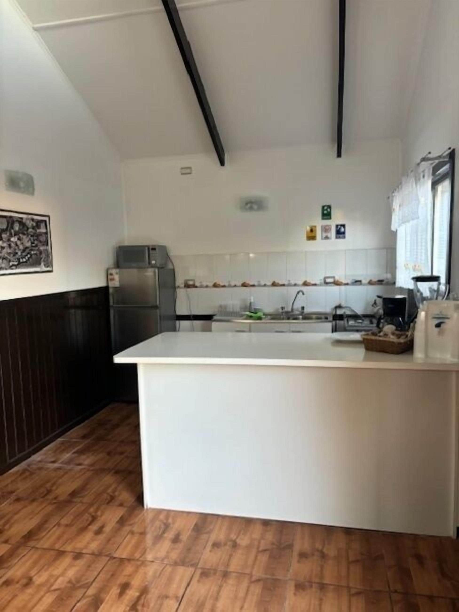 A modern kitchen with a central island, white cabinetry, and a dark wood floor.