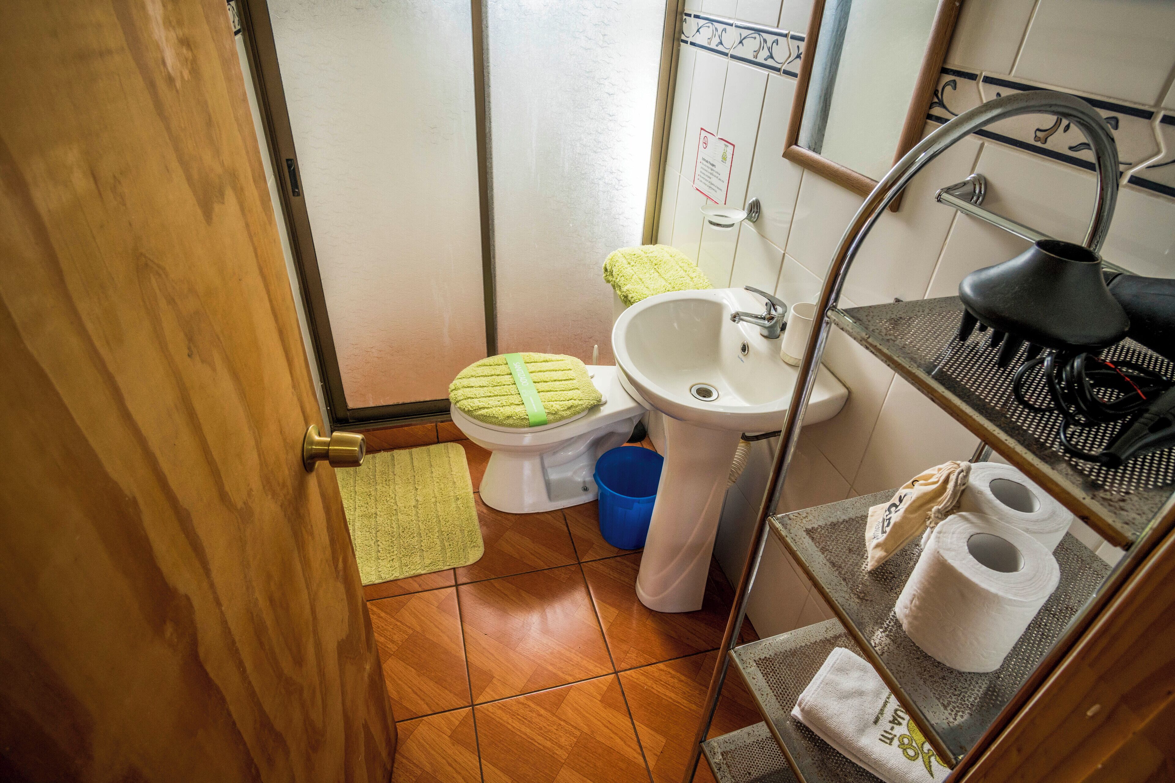 Un baño pequeño con inodoro, lavamanos y un estante con artículos de aseo.