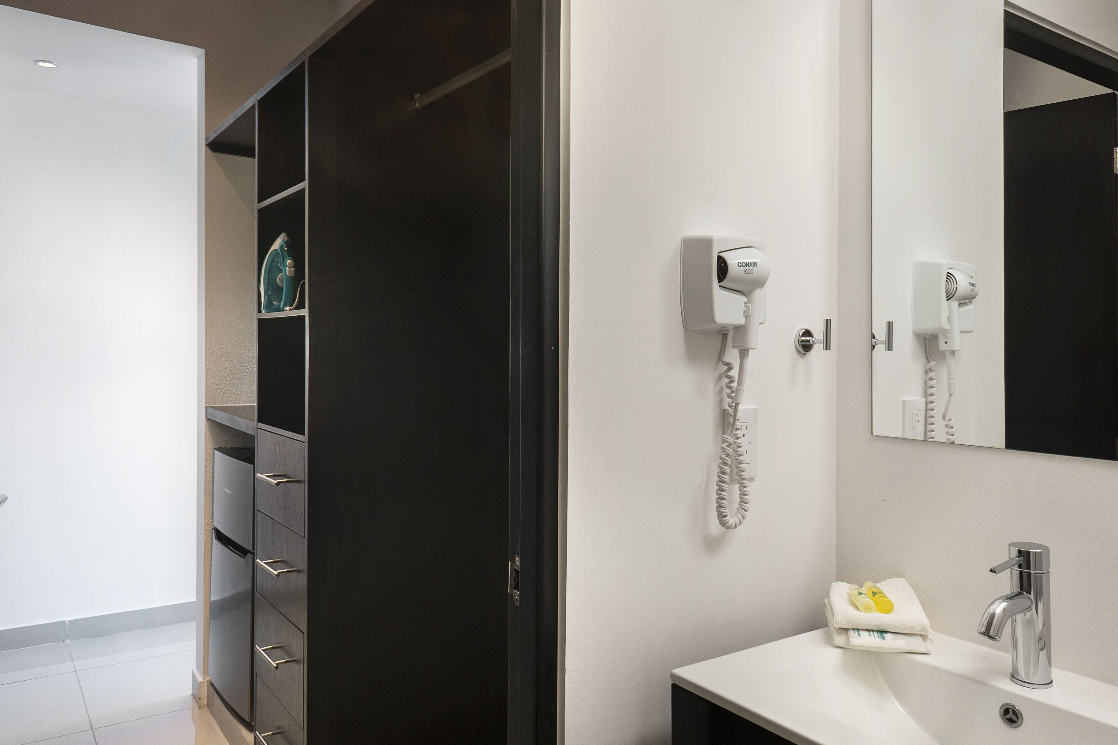 A modern bathroom with a white sink, a mirror, a hairdryer, and a telephone.