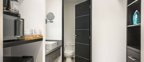 Un baño moderno con cafetera, inodoro y un mueble negro con cajones.
