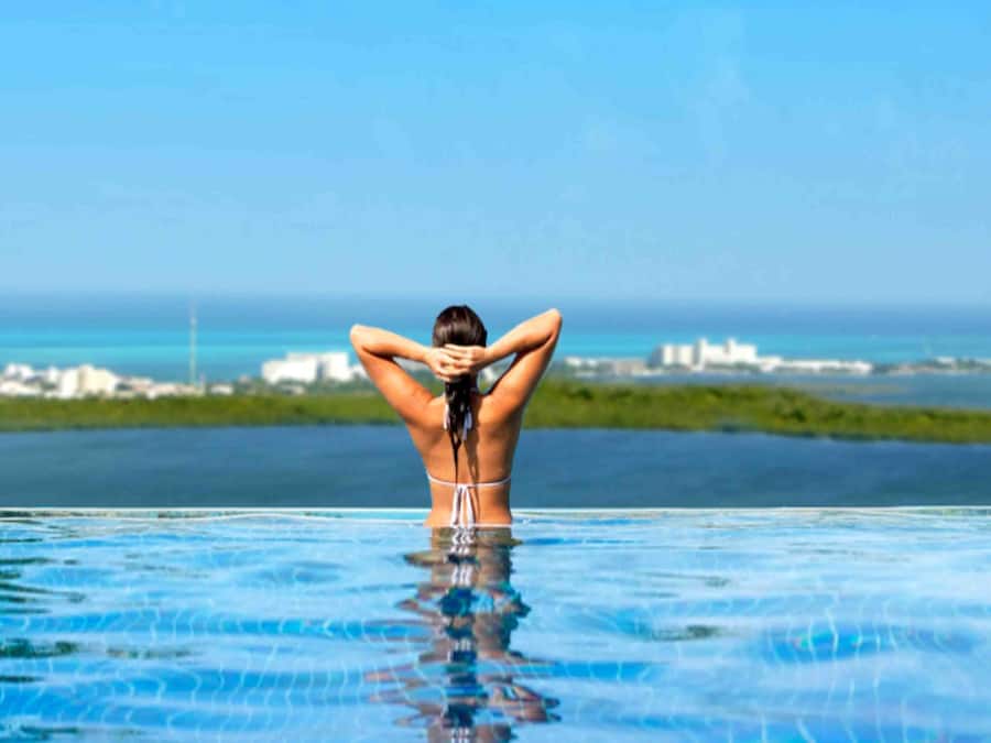 Una piscina al aire libre, sombrillas, sillones reclinables de piscina
