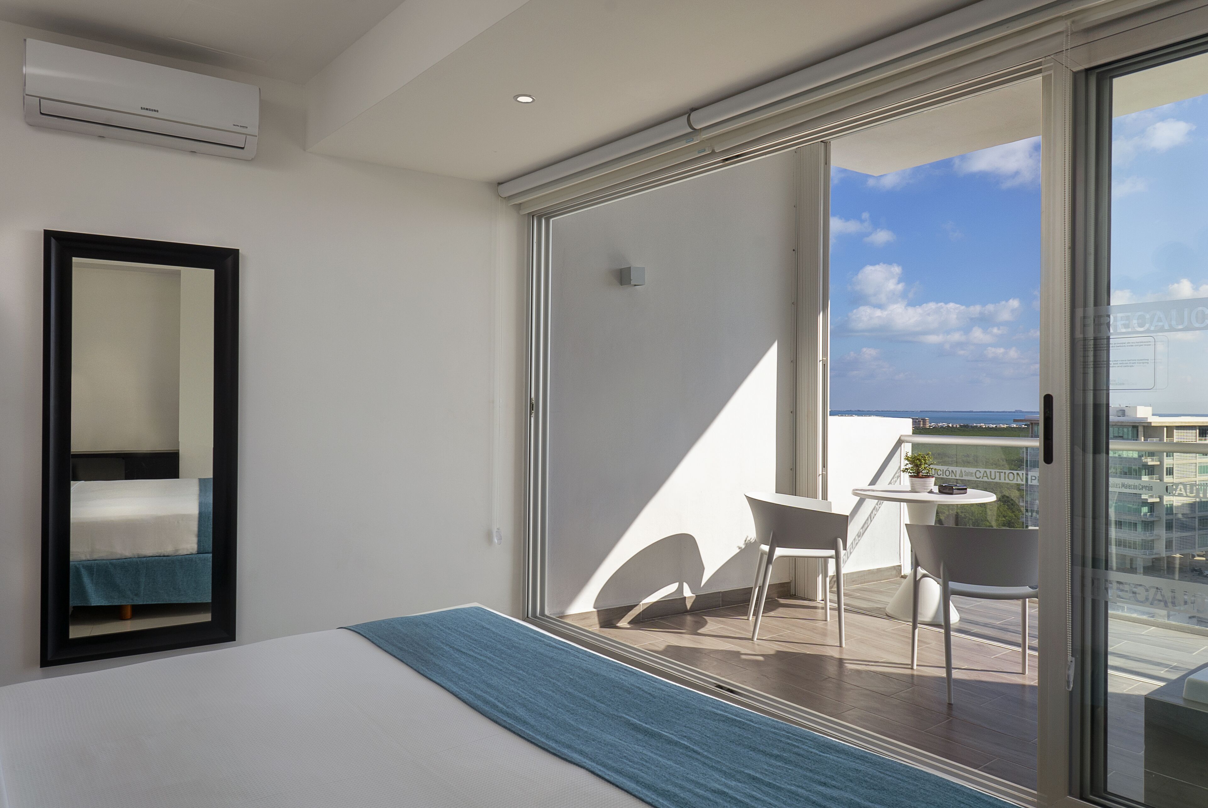 Et hotelværelse med en seng, et stort spejl og en balkon med et bord og stole.