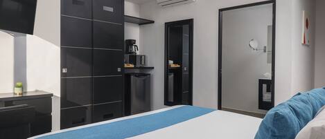 Una habitación de hotel moderna con una cama grande, un escritorio, un armario y un espejo.