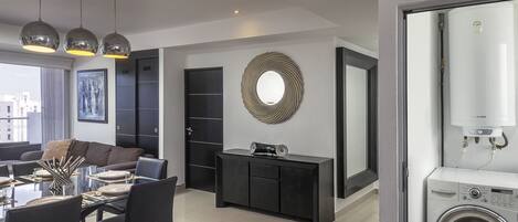 A modern living room with a dining area, a large mirror, and a Bosch washing machine.