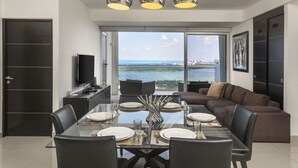 A modern dining area with a glass table, black chairs, and a view of the sea. - Suites Malecon Cancun (Cancun)